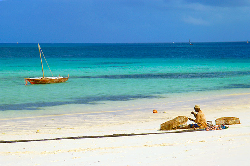 Fisherman repairs fishing net on the beach of Zanzibar, Tanzania